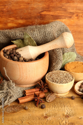Photo: mortar, bowls and spoons with spices, on wooden background mortar, bowls and spoons with spices, on wooden background