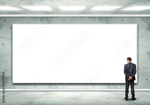 Photo: Business person standing near a blank billboard Business person standing near a blank billboard