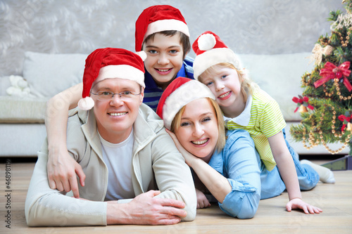 Photo: Portrait of happy family in Christmas hat at home Portrait of happy family in Christmas hat at home