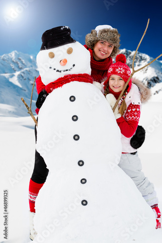 Photo: Winter fun, snowman and happy family Winter fun, snowman and happy family