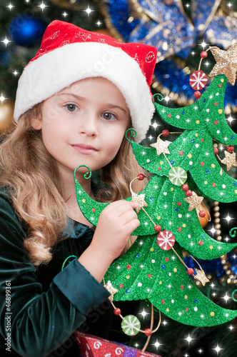 Photo: Christmas - lovely girl in Santa hat with Christmas tree Christmas - lovely girl in Santa hat with Christmas tree