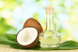decanter with coconut oil and coconuts on green background