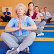 Seniorin macht Entspannungsübung im Fitnesscenter
