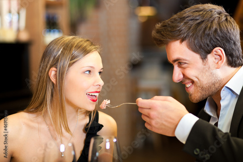 Photo: Romantic couple having dinner, man feeding woman Romantic couple having dinner, man feeding woman
