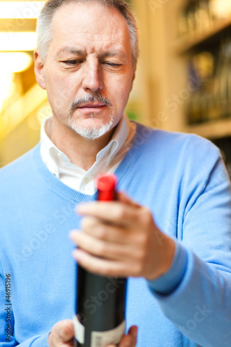 Photo: Man looking at a bottle of wine in a shop Man looking at a bottle of wine in a shop