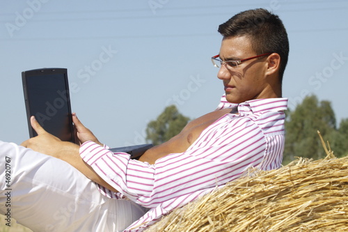 Photo: boy with computers in the field of straw boy with computers in the field of straw