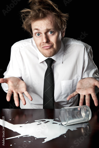 Photo: Helpless businessman with spilled milk on table Helpless businessman with spilled milk on table