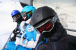 Three skiers in helmets and goggles ride on funicular