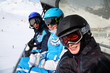 Three happy skiers in helmets and goggles ride on funicular