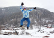 man in ski helmet and goggles jumps on mountain