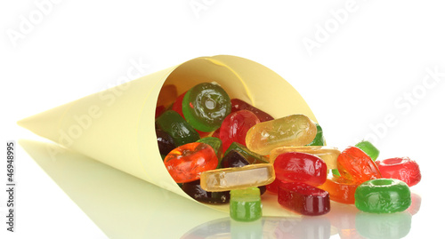 Photo: Tasty colorful candies in bright bag isolated on white Tasty colorful candies in bright bag isolated on white