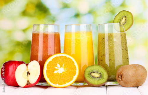 Photo: fresh fruit juices on wooden table, on green background fresh fruit juices on wooden table, on green background