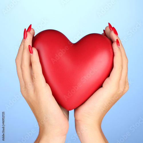Photo: Red heart in woman's hands on color background Red heart in woman's hands on color background