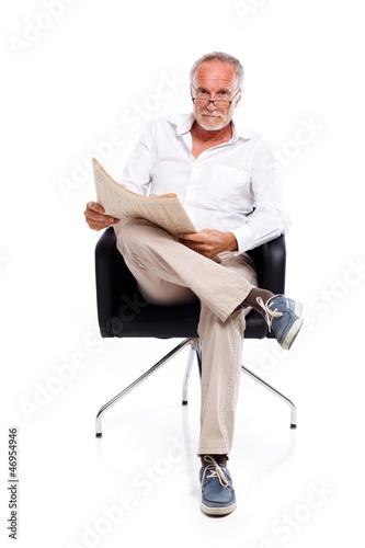 Photo: Casual senior man reading stock rates in newspaper Casual senior man reading stock rates in newspaper
