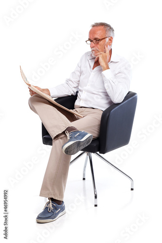 Photo: Casual senior man reading stock rates in newspaper 2 Casual senior man reading stock rates in newspaper 2