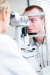 optometry concept - handsome young man having her eyes examined