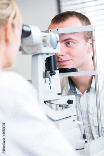 Photo: optometry concept - handsome young man having her eyes examined optometry concept - handsome young man having her eyes examined