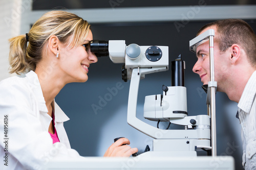 Photo: optometry concept - handsome young man having her eyes examined optometry concept - handsome young man having her eyes examined