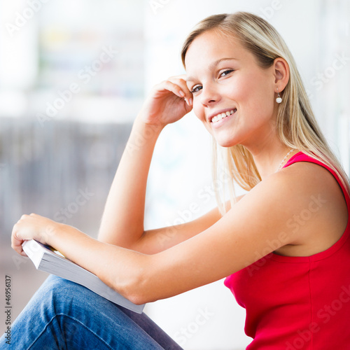 Photo: in the library - pretty female student with books working in a h in the library - pretty female student with books working in a h