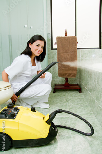 Photo: Young woman steam cleaning the bathroom Young woman steam cleaning the bathroom