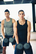 Two young men exercising with dumbbells in the gym.