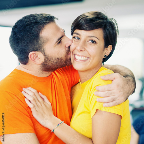 Photo: Young couple embracing and kissing at the gym. Young couple embracing and kissing at the gym.