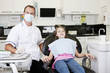 A male dentist with a young girl patient