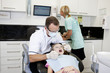 A male dentist examining a young girls teeth