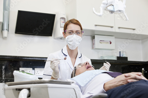 Photo: A female dentist examining a male patients teeth A female dentist examining a male patients teeth