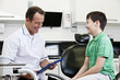 A male dentist talking to a young boy patient