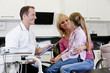 A male dentist talking to a young girl patient and her mother