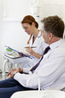 A female dentist discussing dental records with a male patient