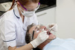 A female dentist examining a male patients teeth, close up