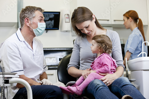 Photo: A male dentist with a little girl patient and her mother A male dentist with a little girl patient and her mother