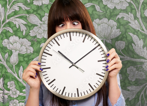 Photo: Woman Holding Clock With Squinted Eyes Woman Holding Clock With Squinted Eyes
