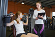 Frau an Schulterpresse mit Fitnesstrainerin