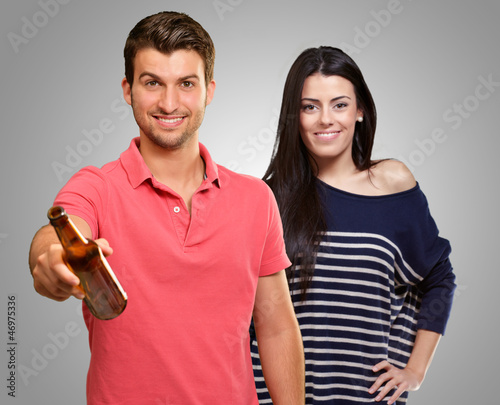 Photo: Young Man Holding Alcoholic Bottle In Front Of Happy Woman Young Man Holding Alcoholic Bottle In Front Of Happy Woman