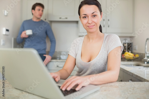 Photo: Young woman using laptop with man drinking coffee Young woman using laptop with man drinking coffee