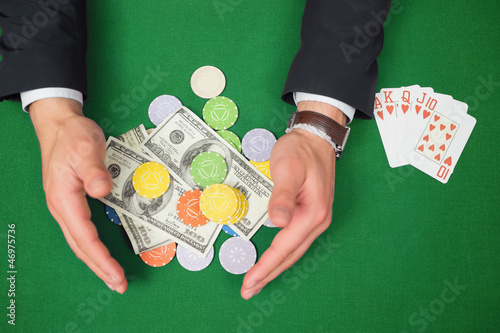 Photo: Hands grabbing dollars and chips from table beside royal flush Hands grabbing dollars and chips from table beside royal flush