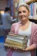 Woman leaning at a bookshelf holding books