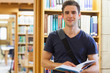 Photo: Man standing at a bookshelf holding a book Man standing at a bookshelf holding a book