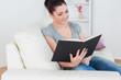 Woman sitting in the living room on the couch and reading