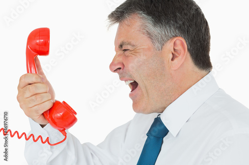 Photo: Businessman screaming in phone receiver Businessman screaming in phone receiver