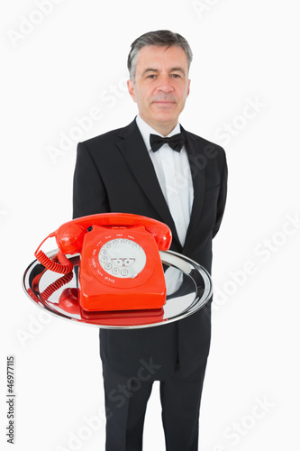 Photo: Well-dressed waiter holding a phone on a silver tray Well-dressed waiter holding a phone on a silver tray