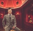 Confident man in classic grey suit sitting on chair in cabinet