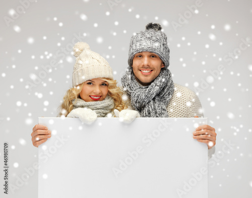 Photo: couple in a winter clothes holding blank board couple in a winter clothes holding blank board