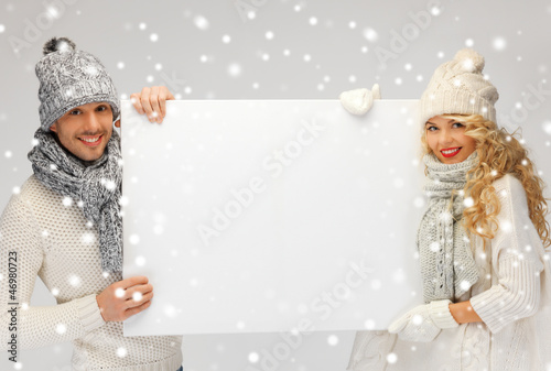 Photo: couple in a winter clothes holding blank board couple in a winter clothes holding blank board