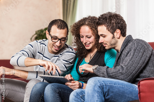 Photo: Three Friends with Tablet PC on a Sofa Three Friends with Tablet PC on a Sofa