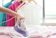 Woman hand ironing a shirt, on cloth background