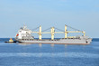 Tugboat assisting bulk cargo ship to harbor quayside